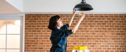 a photo of a woman replacing a light bulb when you need to sell your home fast