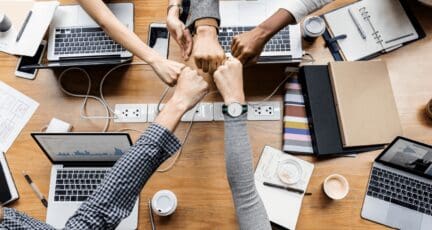 A team of real estate agents joining fists at work.