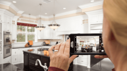 A photo of a woman taking pictures that represents how to take real estate photos and sell faster