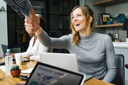 A woman shaking hands after an offer is accepted.