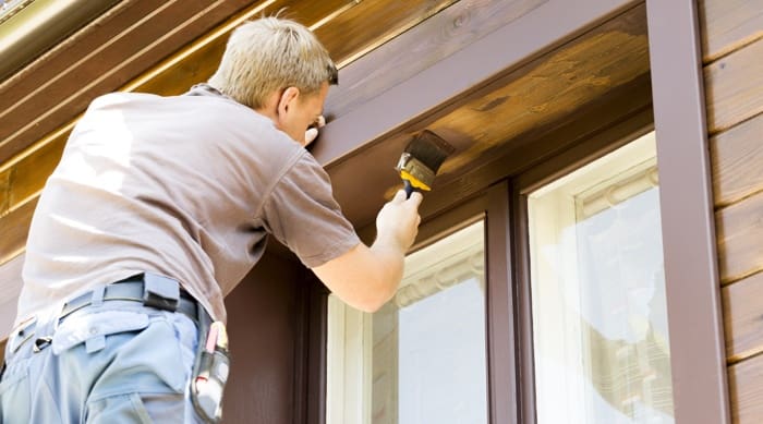 A man maintaining his home by painting the exterior.