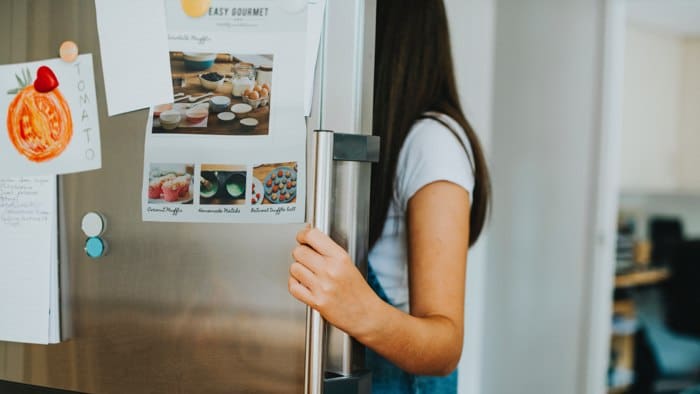 A girl opening a refrigerator that has home repair insurance.