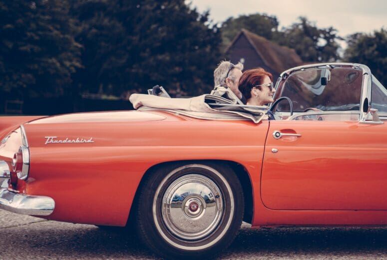 A couple in a red convertible using home equity for retirement.