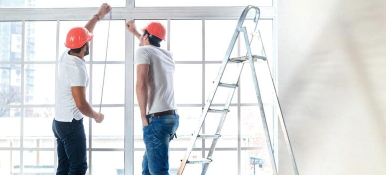 Two contractors repairing windows in house.