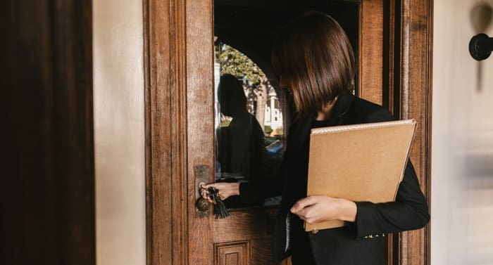 Female real estate agent opening door to open house.