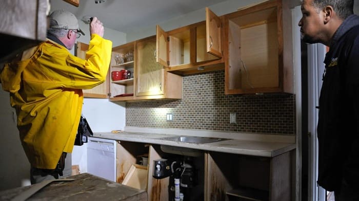 Home inspector in kitchen gathering data for report.