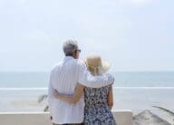 Retired couple looking out at ocean after downsizing.