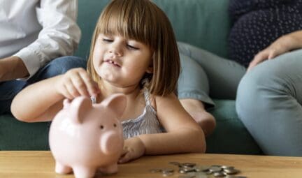 Child putting change in piggy back after downsizing home with family