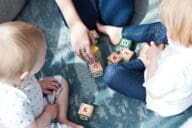 Mother playing blocks with kids in small house.