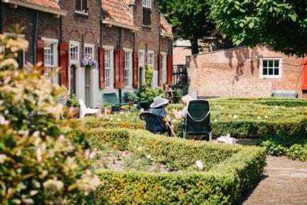 Two people sitting out side rural house with a septic tank.