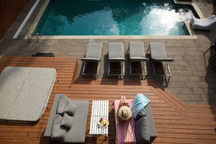 Woman on lounge chair outside house's pool.