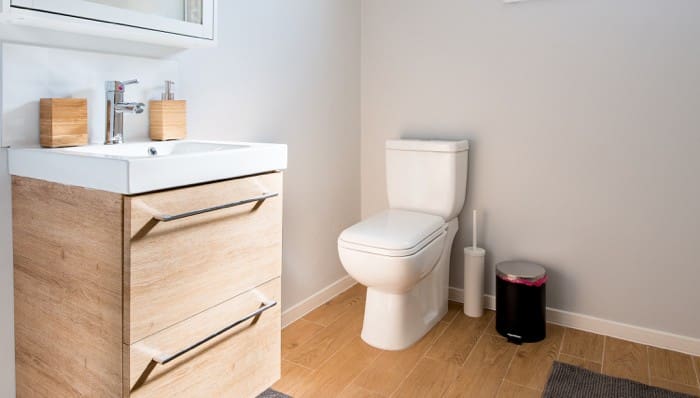 Toilet in home's bathroom with wood floors and finishes.
