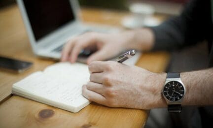 A man writing on a notepad while negotiating a home sale.