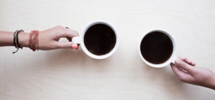 Two people negotiating over a house with two cups of coffee.