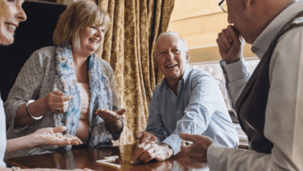 A group of retirees playing in dominoes in a retirement home.