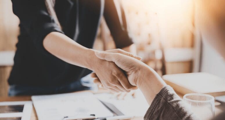 A woman shaking hands after using negotiation tactics to sell real estate.