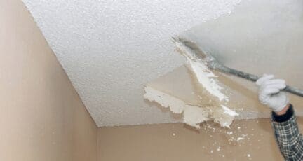 A man removing popcorn ceiling to increase home value.