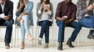 A diverse group of people sitting in a line waiting to hear back on an offer for a house