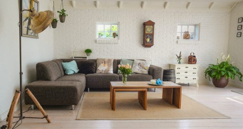 A cozy living room with white brick walls and a brown sofa to symbolize how buying a house is worth it