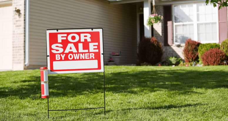 A for sale by owner sign in front of a house.