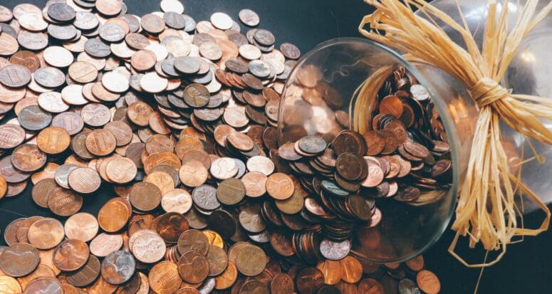 A jar of pennies spilling over a dark floor to represent first-time homebuyer loans