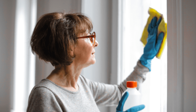 A senior woman cleaning windows just before moving.