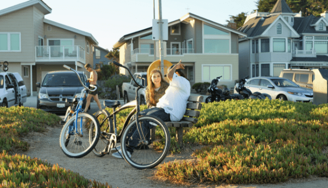 A man and woman with bikes on a path where you can invest in real estate.