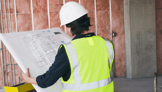 A construction worker looking at development plans.