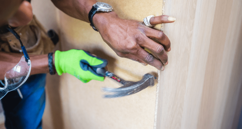 A man using a hammer in order to do home maintenance.