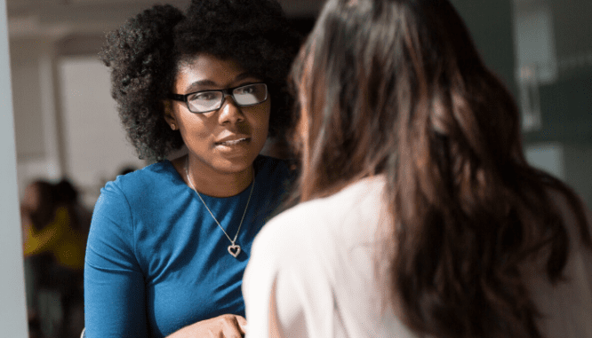 Two women sitting at a table discussing how buying a house works.