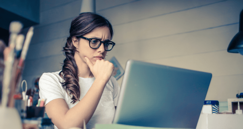 A woman with a look of concern on her face, sitting at a laptop.