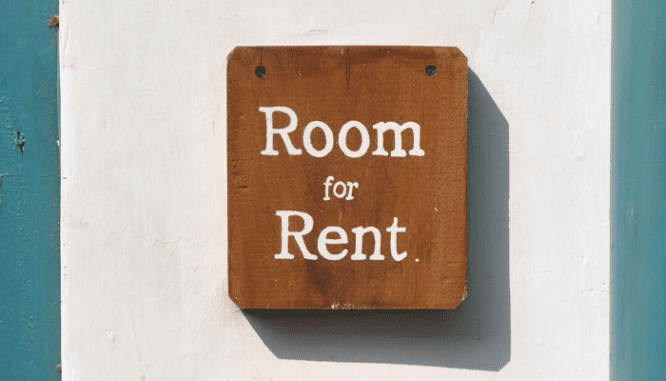 A brown wooden sign that says 'room for rent' on it.