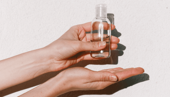 Hands holding a small bottle of hand sanitizer to use for moving during coronavirus.