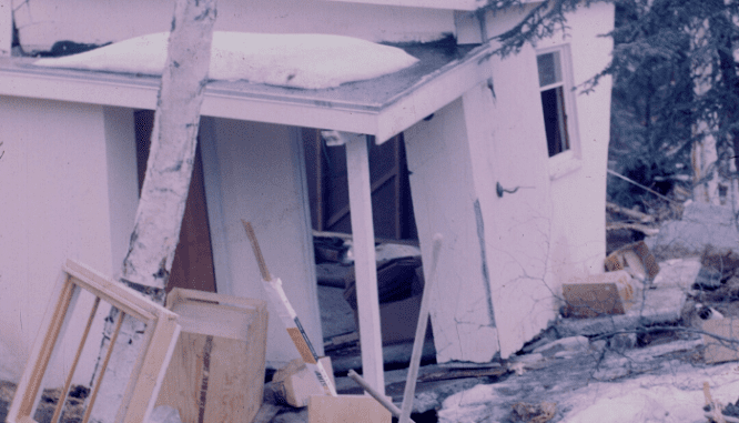 A damaged house with debris around it.