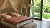 A pink and cream themed bedroom with an open door leading to the backyard.