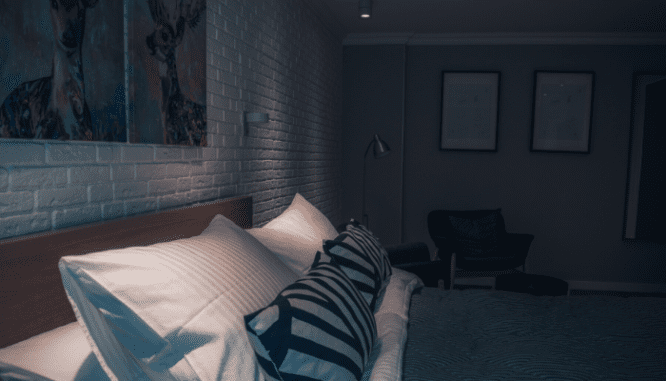 A darkened basement bedroom with a brick wall.