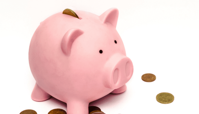 A pink piggybank with assorted coins around it that you could use to save money when moving into a new house.