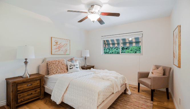 A white-themed bedroom with a ceiling fan and a window, in order to save money when moving into a new house.