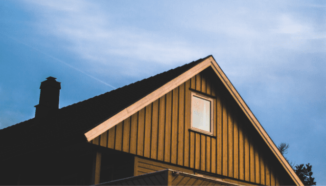 The roof and sky above a brown house that could be an investment.