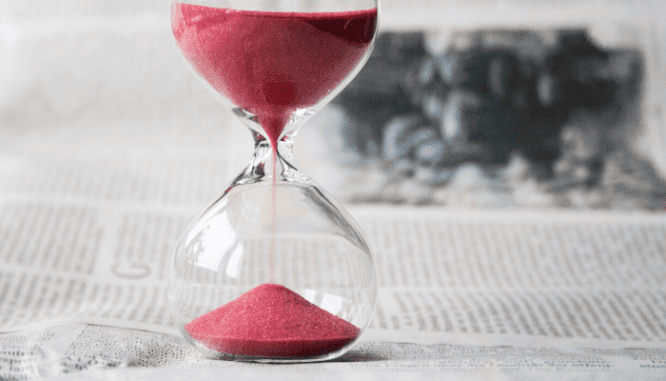 An hourglass with pink sand inside it.