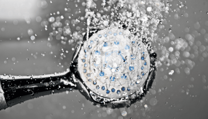 A showerhead spraying water that comes from a tankless water heater.