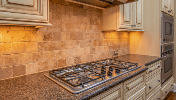 A gas range with a beige tile back splash, a way you could increase home value.