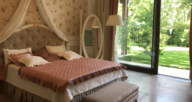 A pink and cream themed bedroom with an open door leading to the backyard.