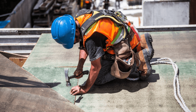 A construction worker nailing something in with a hammer.