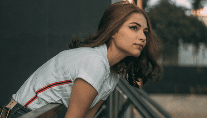 A young woman leaning over a balcony in a white t-shirt wondering about buyer's remorse.