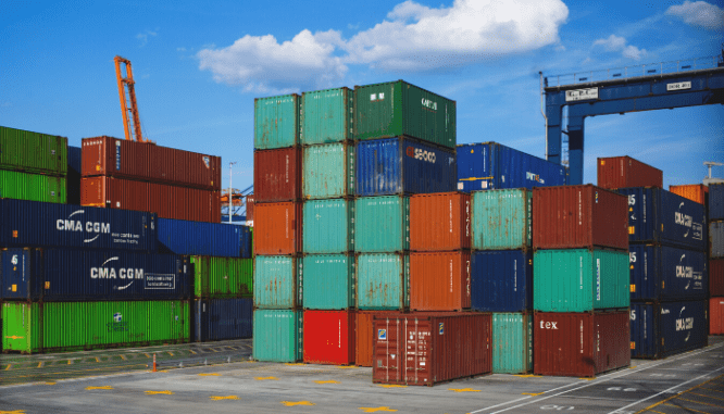 A tower of shipping containers in a shipping yard that you could use to build a house yourself.