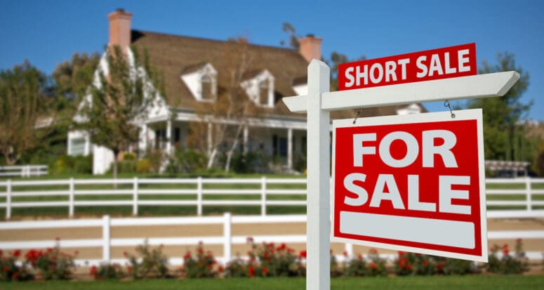 A short sale sign outside of a house for sale, kickstarting the short sale buying process