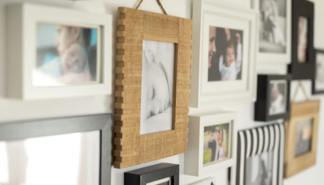 Family portraits on a gallery wall are one way to arrange wall art in a new house