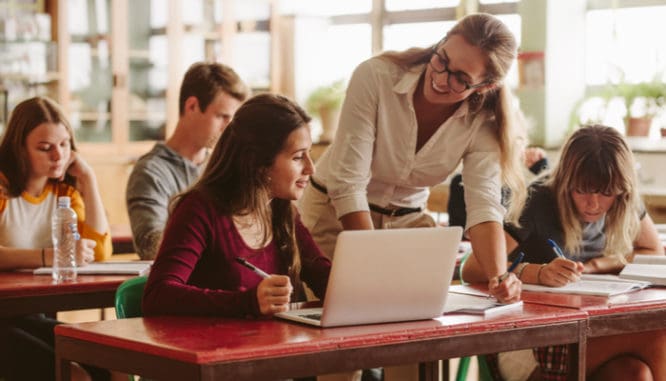 a teacher helping a student in a classroom; teachers are eligible to buy a house without paying pmi