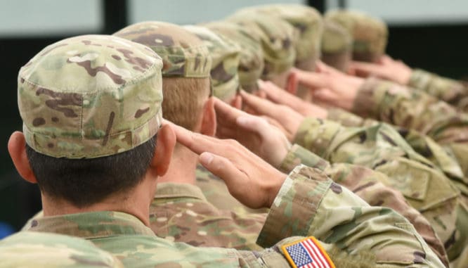 A row of men in military uniforms saluting; veterans can buy a house without having to pay PMI